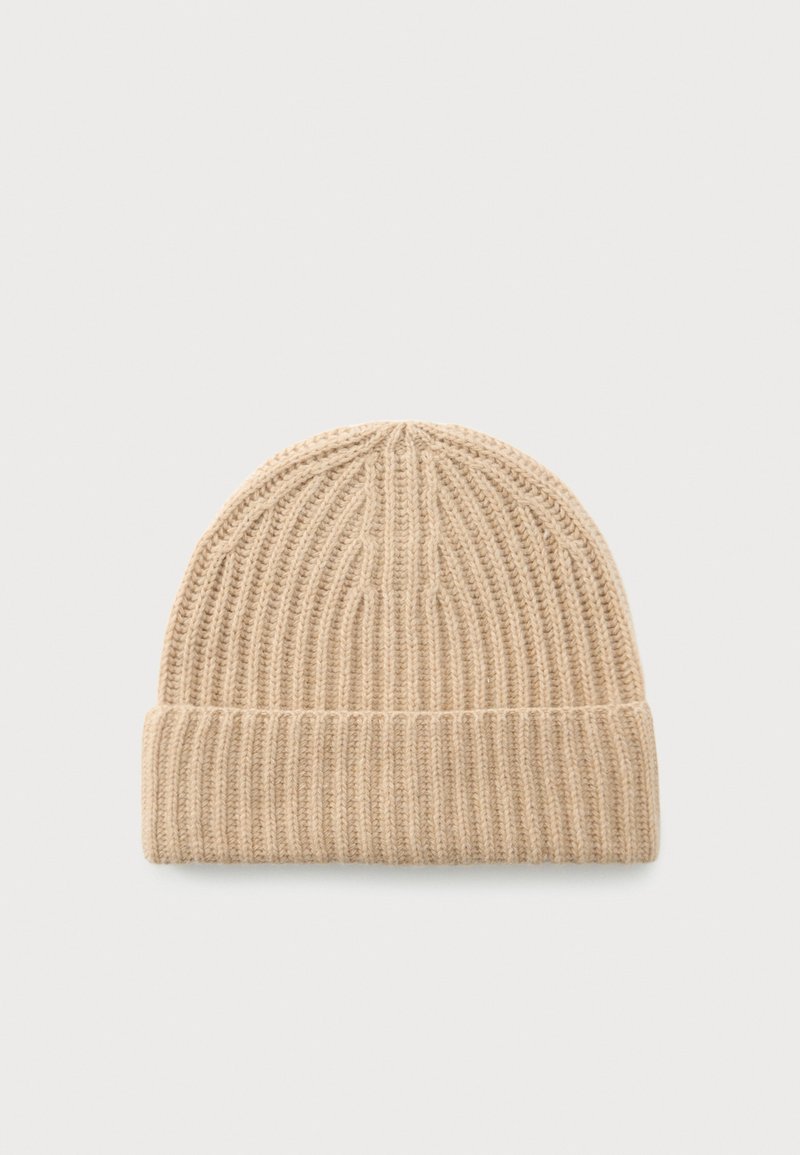 Kreemja ribakudumine beanie müts, millel on volditud ääreosa, asetatud tasasele taustale.