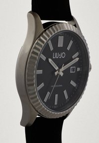 Runde schwarze Uhr mit silbernem Gehäuse, einem dunklen Zifferblatt, silbernen Stundenmarkierungen und Datumsanzeige. Hergestellt mit einem schwarzen Armband.