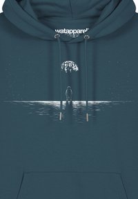 Türkise Kapuzenjacke mit Kordelzügen und silbernen Ösen. Mit einem weißen Grafikmotiv eines Körpers vor einem großen Mond über einer wasserähnlichen Oberfläche.