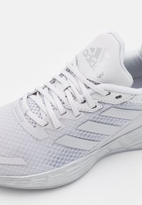 Scarpa da ginnastica bianca con tomaia in rete, dettagli testurizzati e tre righe tono su tono. Chiusura con lacci standard e colletto e linguetta imbottiti.
