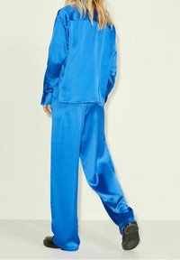 Blue satin loungewear set featuring a loose-fitting top and wide-leg pants, showcasing a smooth texture and a relaxed silhouette.