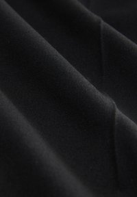 Tessuto nero con una texture liscia e opaca, caratterizzato da pieghe subtle e un aspetto uniforme e costante su tutta la superficie.