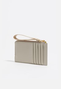 Tarjetero de cuero gris claro con cierre de cremallera, que cuenta con cuatro ranuras verticales para tarjetas y una correa para la muñeca texturizada. Acabado suave, diseño minimalista.
