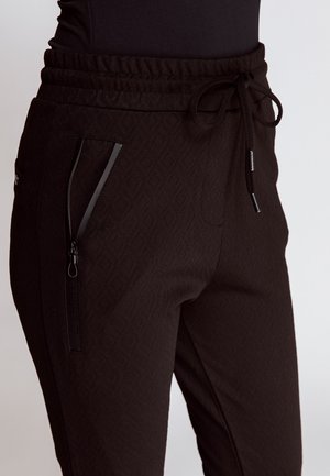 Black joggers with a textured diamond pattern, elastic waistband, drawstring detail, and zippered side pockets with glossy accents.