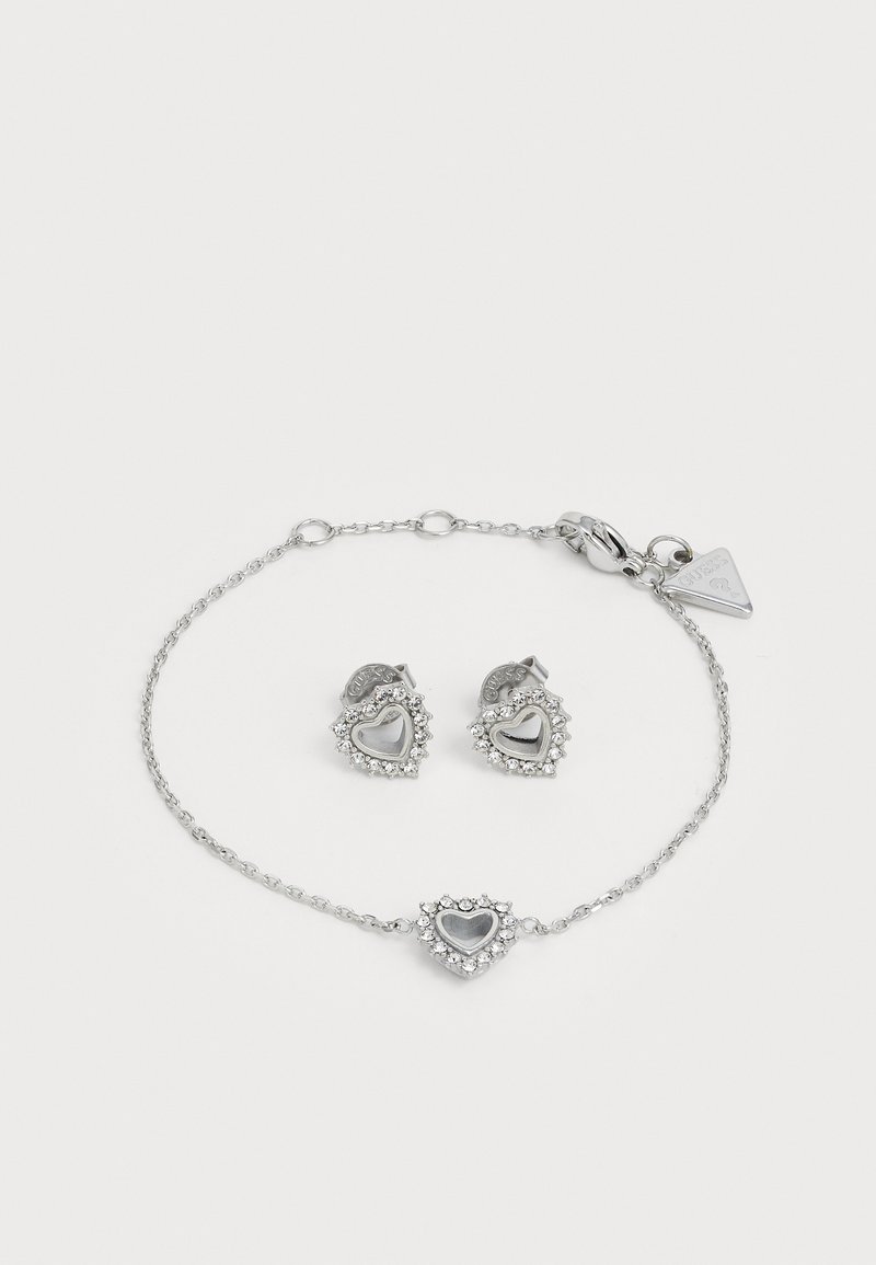 Zilveren sieradenset met hartvormige oorringen en een bijpassende armband, versierd met heldere kristallen en een delicate kettingontwerp.