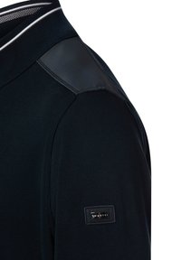 Granatowy sweter dziergany z teksturowanej tkaniny, z skórzanymi akcentami na ramionach i prążkowanym kołnierzem. Z boku znajduje się metka "bugatti".