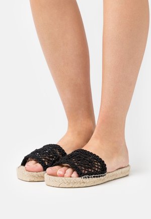 Sandales d'été noires en crochet avec un dessus tissé et une semelle en jute naturel. Présentent un design à bout ouvert et des détails texturés.