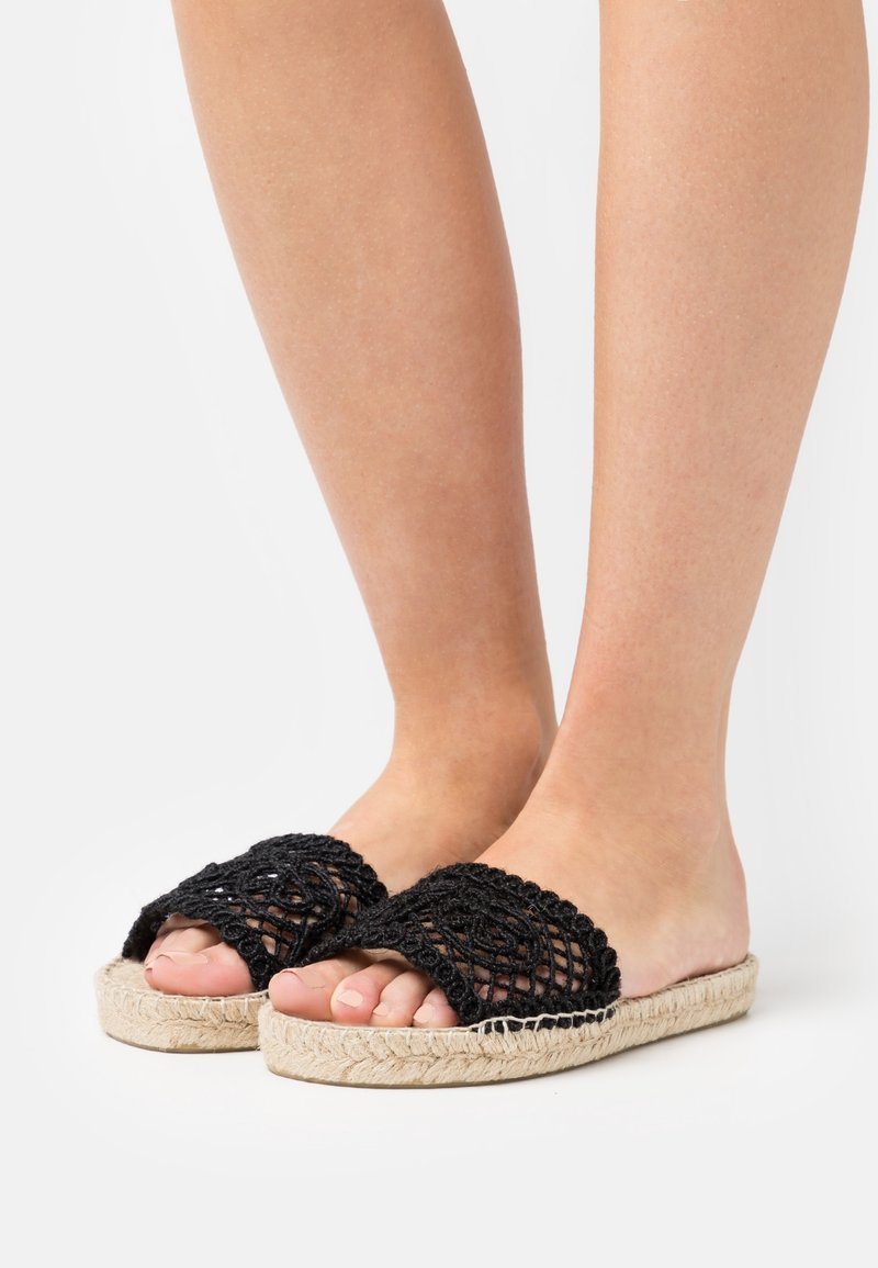 Černé háčkované pantofle s tkaninou na svršku a přírodní juteovou podrážkou. Disponují otevřenou špičkou a texturovanými detaily.