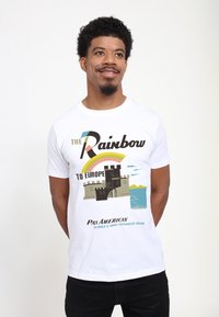 Vit bomulls-T-shirt med en grafisk design av ett slott, regnbåge och text i olika färger, med Pan American-logotypen längst ner.