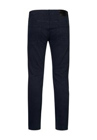 Jeans de un azul oscuro con un diseño ajustado, que cuentan con bolsillos traseros y un parche de cuero negro texturizado en la cintura.