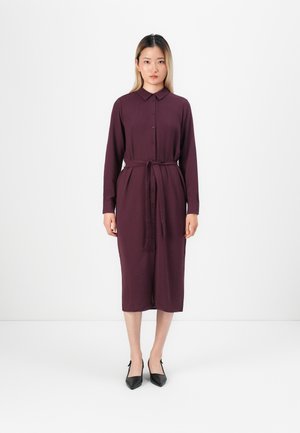 Bordo sukienka koszulowa z długimi rękawami, paskiem w talii i bocznymi kieszeniami. Czarne szpilki w szpic dopełniają całość. Minimalistyczny design.