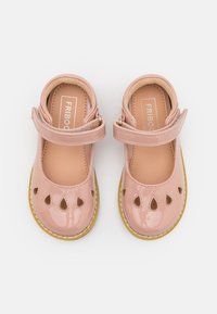 Zapatos Mary Jane de charol rosa sonrosado con detalles recortados, correa ajustable, plantilla beige y suela de goma amarilla.