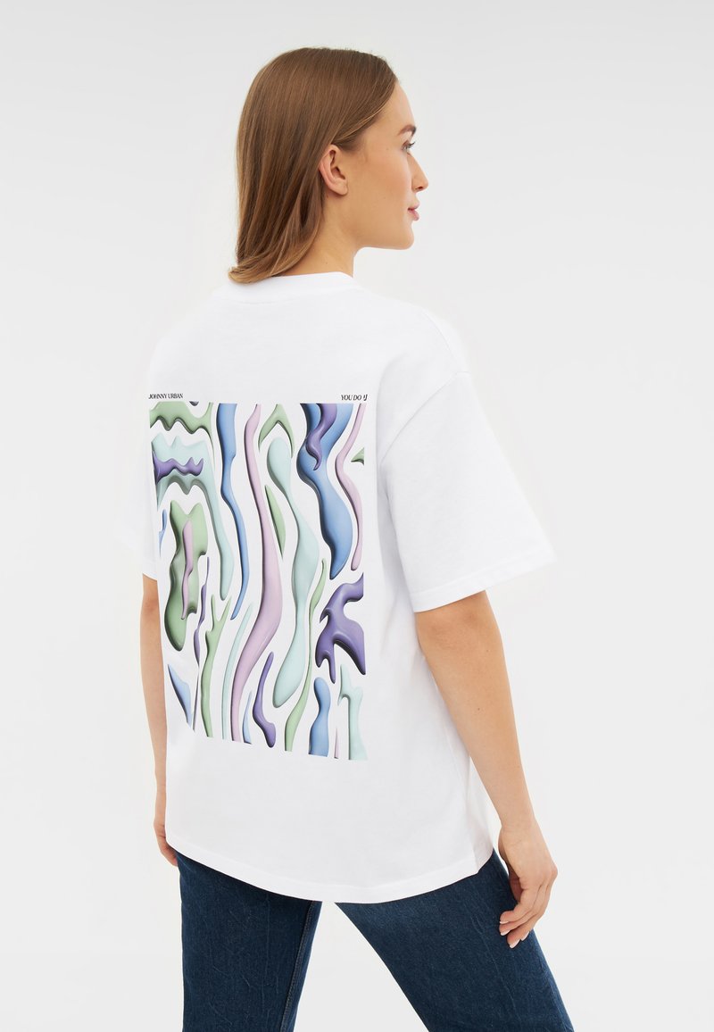 Camiseta blanca de gran tamaño con un diseño abstracto colorido en la parte posterior, con patrones ondulados en tonos verdes, púrpuras y azules.