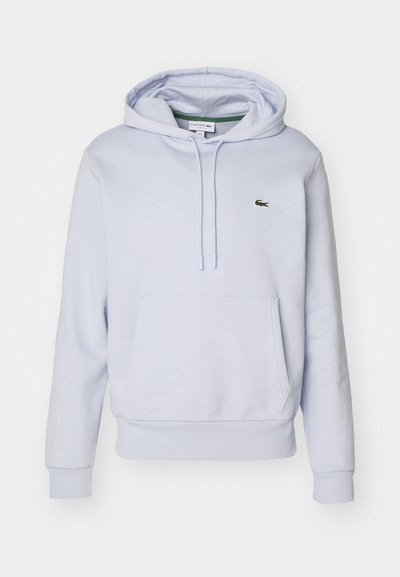 Haut de survêtement bleu clair en coton, doté d'une poche kangourou, d'une capuche avec cordon de serrage et d'un petit logo vert Lacoste sur la poitrine.