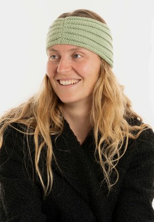 Lichtgroene gebreide haarband met getextureerde strepen. Draagt een persoon met lang haar, tegen een witte achtergrond.