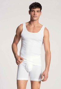 Witte katoenen tanktop en bijpassende boxers, met een geribbelde textuur en een strakkere pasvorm. De tanktop heeft brede schouderbanden en een ronde halslijn.