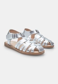 Zilverkleurige metalen sandalen met een geweven ontwerp, open teen, verstelbare enkelband en een bruine rubberen zool.
