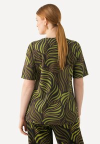 Camicia a maniche corte in tessuto marrone scuro con motivi a foglie verdi. Vestibilità rilassata con scollo rotondo e taglio dritto all'orlo.