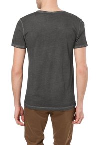 Šedé tričko s krátkým rukávem a volným střihem, s kulatým výstřihem a mírně opotřebovanými detaily na látce. Materiál z bavlněné směsi.