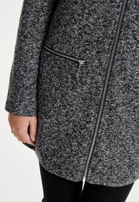 Cappotto in tessuto grigio con dettagli neri, con cerniera visibile e due tasche laterali con cerniera. Design a vestibilità regolare con maniche lunghe.