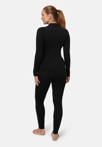 Completo sportivo nero composto da una maglietta a maniche lunghe con un design aderente e leggings abbinati. Tessuto elasticizzato con cuciture minime.