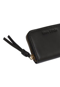 Portefeuille en cuir noir avec texture lisse, fermeture éclair et tirette en cuir décorative. Nom de la marque embossé à l'avant. Accents de zipper doré.