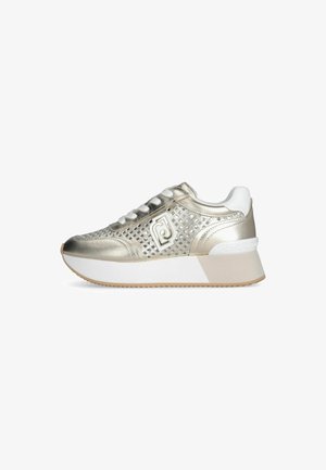 Sneaker metallico oro con design in rete, accenti bianchi, suola bianca spessa e punta arrotondata. Presenta un marchio decorativo sul lato.