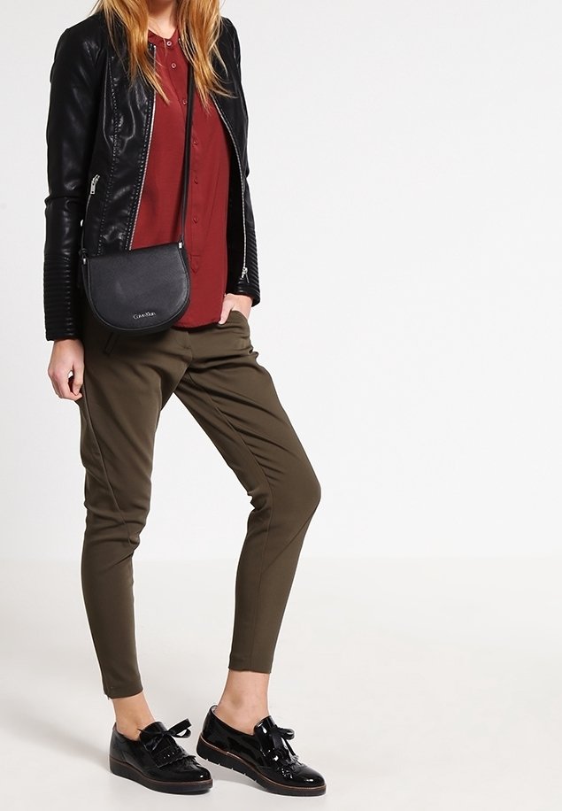 Czarna skórzana kurtka, bordowa koszula z guzikami, oliwkowe zwężane spodnie i czarne lakierowane buty z kokardkami, w połączeniu z czarną torebką na ramię.