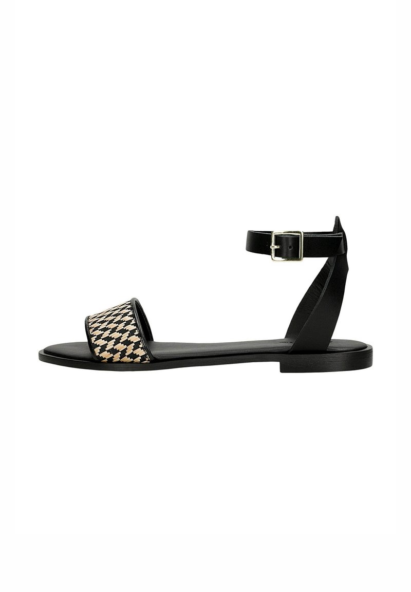 Black flat sandals featuring a woven patterned strap in beige and black, an ankle strap with a buckle, and a minimalistic design.