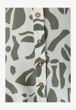 Zielony abstrakcyjny wzór na białej tkaninie o miękkiej teksturze, z brązowymi guzikami wzdłuż centralnego przodu do zapięcia.