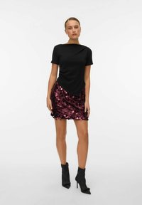 Črno kratkosekharnasto majico so združili z burgaatno bleščečo mini krilo. Črneškornike na visoki peti dopolnjujejo obleko in poudarjajo čisto silhueto.