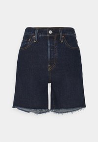 Mörka denimshorts med hög midja, med gula sömmar, fransad nederkant och fem fickor. Knapplist fram.