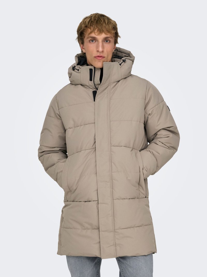 Beige padded parka with a high collar, front zip closure, and two side pockets. Features adjustable hood and subtle stitching patterns.