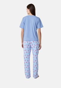 T-shirt in cotone azzurro abbbinato a pantaloni del pigiama blu e bianchi a scacchi con motivi di ciliegie rosse. Design semplice e dal taglio rilassato.