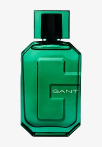 Green glass fragrance bottle with a geometric design, featuring a prominent "G" and white text spelling "GANT." Black cap on top.