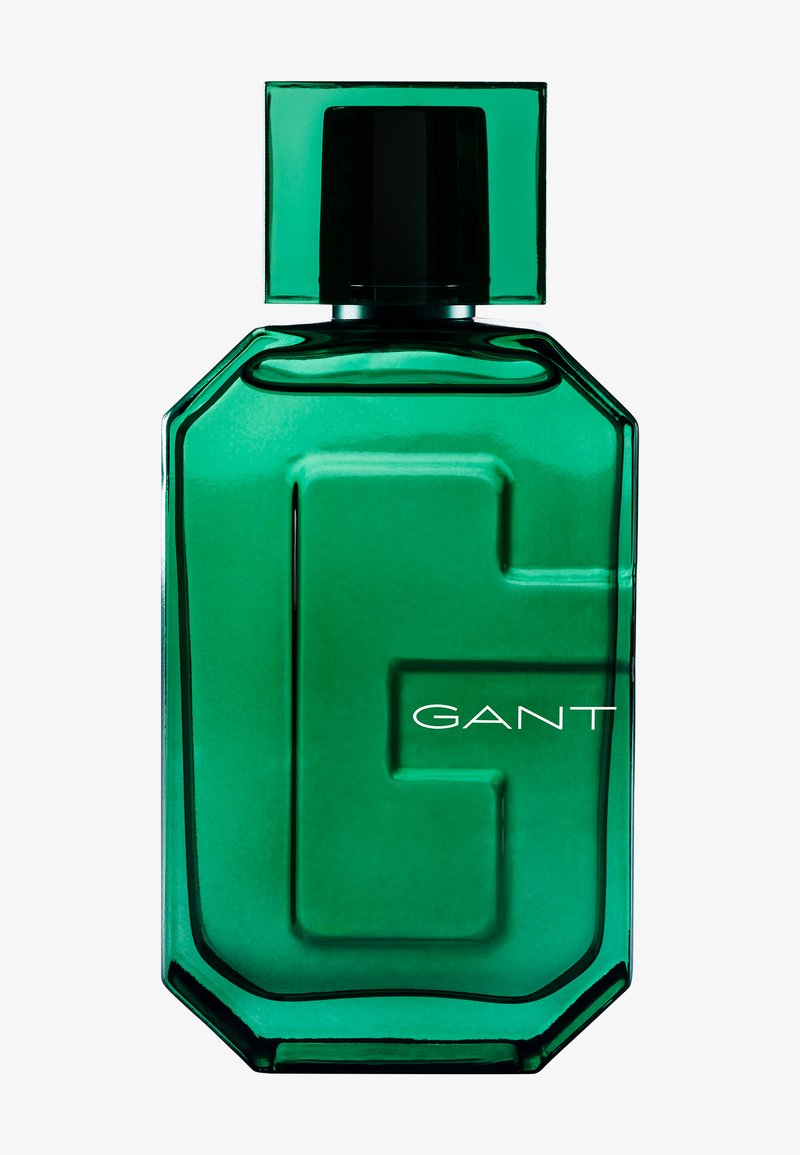Green glass fragrance bottle with a geometric design, featuring a prominent "G" and white text spelling "GANT." Black cap on top.