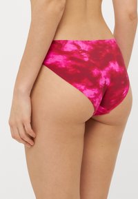 Rózsaszín batikolt bikini alsó, magas szabású kialakítással. Sima anyag, varrat nélküli szélek és enyhe fényes textúra.