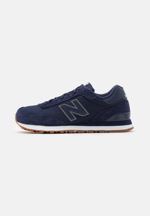 Granatowy sneaker New Balance z cholewką ze skóry zamszowej i siateczki, białą śródstopką, gumową podeszwą zewnętrzną oraz logo na boku i pięcie.