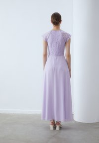 Blonde og chiffon kjole i lys lavendel med en tettsittende bodice og utsvakt skjørt. Den har korte ermer og en skjult glidelås bak.