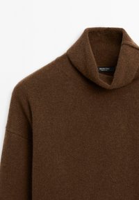 Brown turtleneck sweater made of textured knit fabric, featuring a high collar and drop shoulder design. Label visible inside collar.