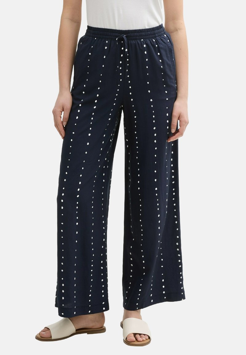Navy wide-leg pants with a drawstring waist, featuring vertical white dot patterns and soft fabric. Paired with light sandals.