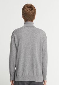 Grå polotröja med avslappnad passform, med ribbade cuffs och nederdel, mjuk textur och sänkta axlar för avslappnad komfort.