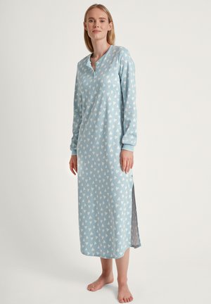 Camicia da notte azzurro chiaro con un motivo a cuori bianchi su tutta la superficie, maniche lunghe, una patta con bottoni e aperture laterali per facilitare i movimenti.