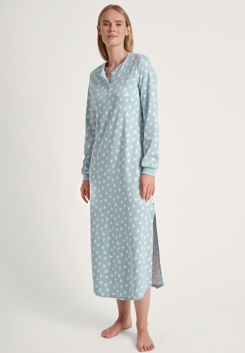 Lichtblauw nachtjurk met een overal wit hartpatroon, lange mouwen, een knoopsluiting en zijsplitsen voor gemakkelijke beweging.