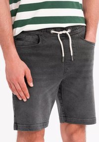 Harsojin denim-shortsit, joissa on sivutaskut, joustava vyötärö ja säädettävä nyöri. Sileä pinta ja hillitty haalistunut viimeistely.