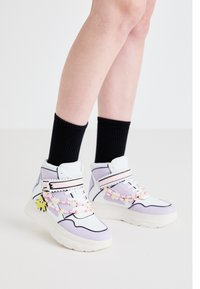 Sneakers wysokie w białym i lawendowym wzorze, z różowymi koralikowymi akcentami i zawieszką w kształcie gwiazdy, na tle czarnych skarpetek w prążki.