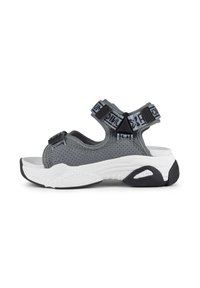 Sandales en maille grises avec des sangles ajustables, semelle intermédiaire blanche épaisse, semelle extérieure noire et un détail de matériel distinct sur les sangles.