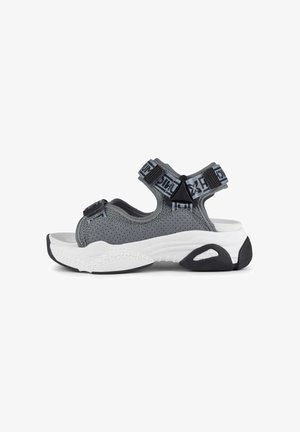 Sandalo in rete grigia con cinturini regolabili, suola intermedia bianca spessa, suola nera e dettagli hardware distintivi sui cinturini.