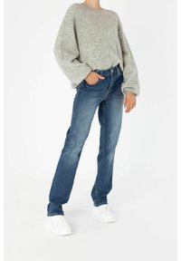 Šedý oversized svetr s texturovanou tkaninou, ve spojení s modrými denimovými džíny se straight-leg střihem a bílými teniskami. Jednoduchý a ležérní outfit.