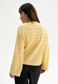 Geel gebreid sweater met een gestructureerd gestreept patroon, brede mouwen en een cropped pasvorm. Ribgebreide halslijn en manchetten.
